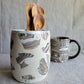 Marble-patterned ceramic mug with wooden utensils on a textured surface