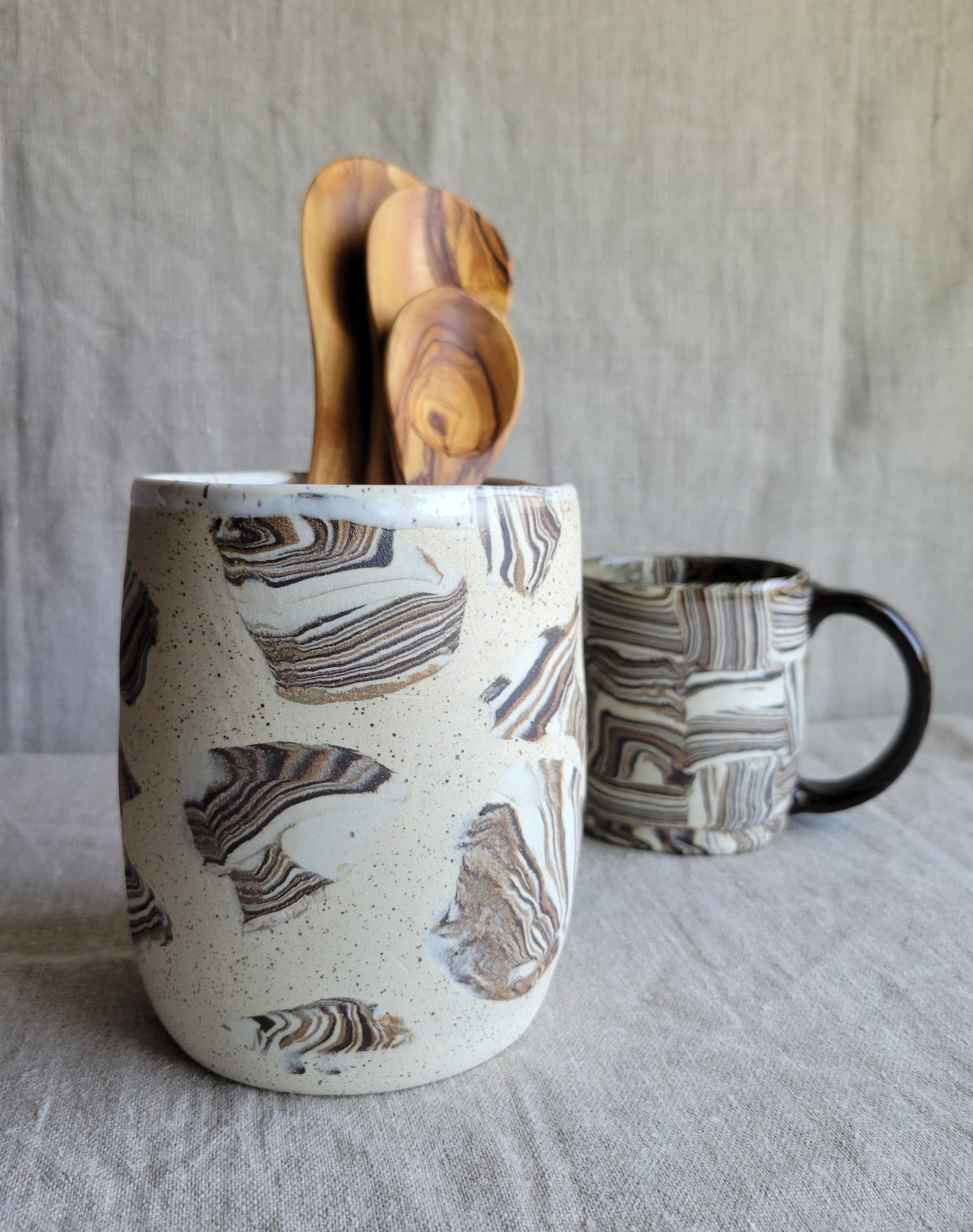 Marble-patterned ceramic mug with wooden utensils on a textured surface
